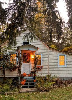 a small white house with pumpkins on the porch