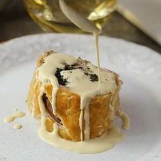 a white plate topped with a pastry covered in icing and drizzled