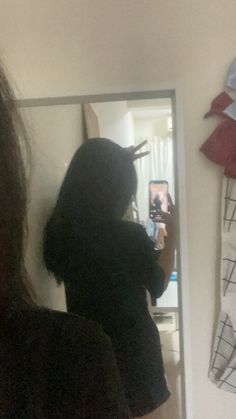 a woman taking a selfie in front of a mirror with her hair combed