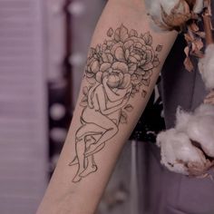 a woman's arm with a tattoo on it and flowers in the middle of her arm