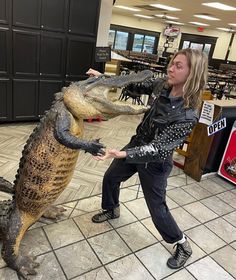 a woman standing next to an alligator statue