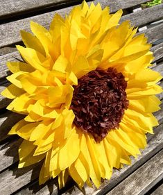 a large sunflower sitting on top of a wooden bench