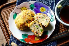 two muffins on a plate next to a cup of tea and chopsticks