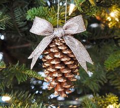 a pine cone ornament hanging from a christmas tree with a bow on it