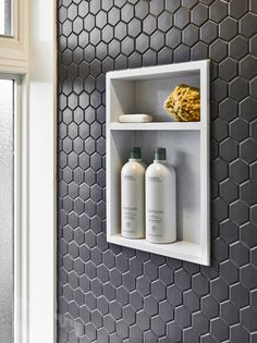 a shelf with two bottles and soaps on it in front of a tiled wall