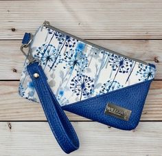 a blue and white purse sitting on top of a wooden table next to a keychain