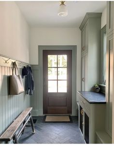 a long hallway with a bench, coat rack and entryway to another room in the house