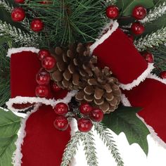 a pine cone on top of holly with red and white decorations