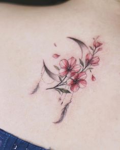 a woman's upper back tattoo with flowers and crescent moon on her left side