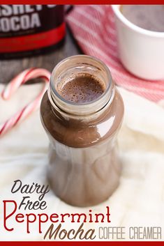 a glass jar filled with hot chocolate next to a cup of coffee