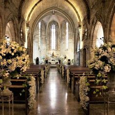 the interior of an old church with pews and floral arrangements on each side of the aisle