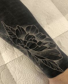 a black and white flower tattoo on the arm