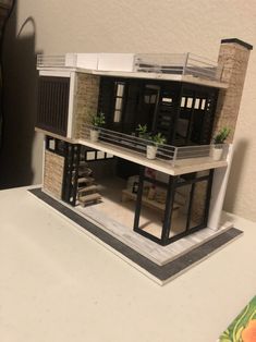 a model of a two story house with plants on the balcony and stairs to the second floor