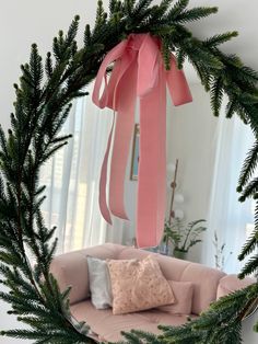 a round mirror with pink ribbon hanging from it's side and a couch in the background