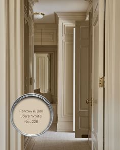 an empty hallway with white walls and beige trim on the door, along with a circular sign that says farrow & ball join's white no 223