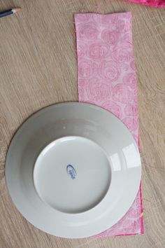 a white plate sitting on top of a table next to a piece of pink paper