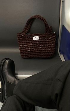 a person's legs and handbag sitting on the seat of an airplane or train