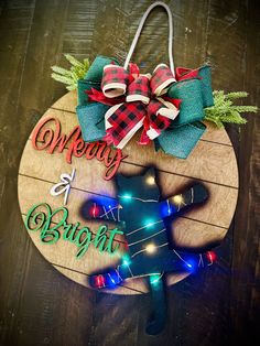 a christmas ornament hanging on a wooden board with lights around it that says merry and bright