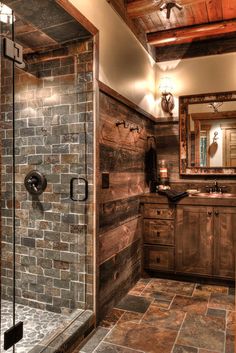 a rustic bathroom with stone flooring and wooden walls, along with a walk in shower