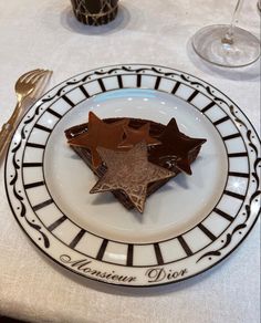 three chocolate stars on a white plate with silverware