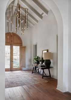 a room with a chandelier hanging from it's ceiling and wooden floors