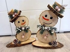 two snowmen made out of wood with pine cones