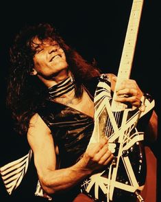 a man with long hair playing an electric guitar