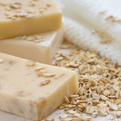 three bars of soap sitting on top of a white surface next to some oats