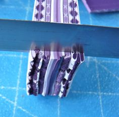 some purple and white striped paper on a blue counter top with scissors in it's hand