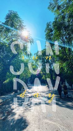 the words sun day are written in front of trees and people walking down the street