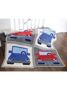 a crocheted blanket with cars on it in the middle of a wooden floor