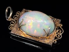 "In this one of a kind opal pendant, we've married two incredible, valuable pieces. The frame is rose gold, dating to the Victorian Era, with flowing milgrain details that give the piece an Etruscan feel! This incredible opal is one of the prettiest in our collection, featuring an incredible play of color, with flashes of orange, red and green.  Known for their green fire and amazing clarity, Ethiopian opals are prized the world over. This is a bold statement piece of the highest quality that will be treasured for years to come.  This pendant does not come with the chain shown. Please feel free to contact us, we will help you find the perfect chain for your style and budget! Metal: 14K Antique Rose Gold Gem: Ethiopian Opal 29.79 Carats  Gem Measurements: 26 x 20 mm, Oval  Measures: 50 x 24 Opal Necklaces, Vintage Jewellery Rings, Green Fire, Opal Pendant Necklace, Stone Feature, Antique Roses, Yellow Gold Chain, Opal Pendants, Opal Necklace