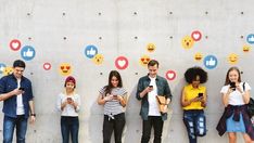 several people standing in front of a wall with emoticions on it