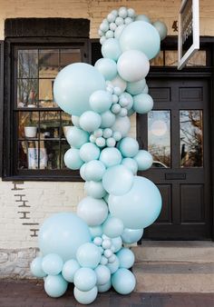 a bunch of balloons that are in front of a building with a door and windows