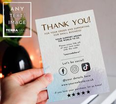 a person holding up a thank you card in front of a vase with flowers on it