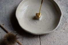 a small white bowl with a tiny heart on the inside and a dandelion in the middle