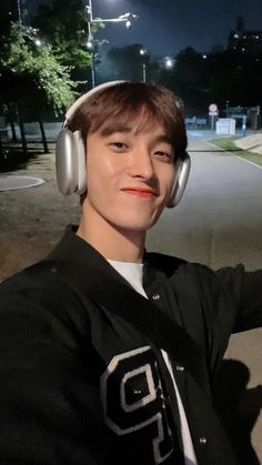 a young man wearing headphones sitting on the side of a road in front of a street light