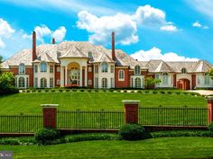 a large brick and iron fence in front of a big house with lots of windows