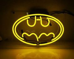 a neon batman logo is shown on the wall in front of a light that has been turned yellow