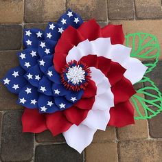 an american flag pinwheel laying on top of a brick floor next to green leaves