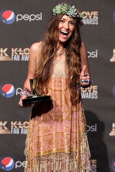 a woman in a dress holding an award and giving the peace sign with her hand