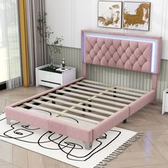 a bed with pink upholstered headboard sitting on top of a white rug