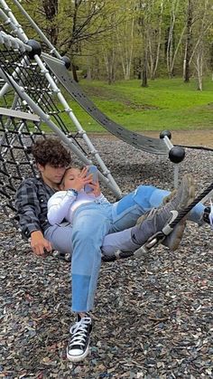 a man holding a baby while sitting on a swing