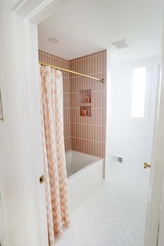 a bathroom with pink and white tiles on the walls, shower curtain in the bathtub