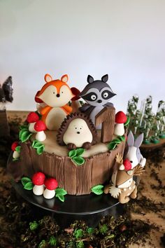 there is a cake decorated with animals and mushrooms on the top of a tree stump