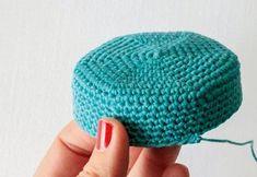 a woman's hand holding a small crocheted hat