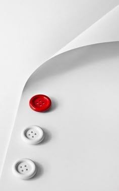 three red and white buttons on a white surface with curved lines in the back ground