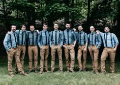 a group of men standing next to each other in front of some trees and grass