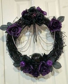 a wreath with purple flowers and pearls hanging on a white door frame in the shape of a ball