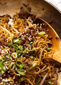 a wooden spoon filled with noodles and meat